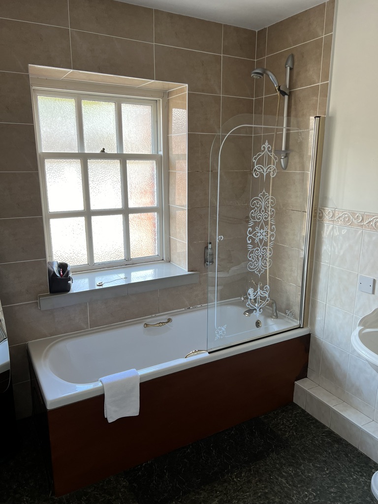 Bath with glass shower screen in an ensuite bathroom at The Silk House