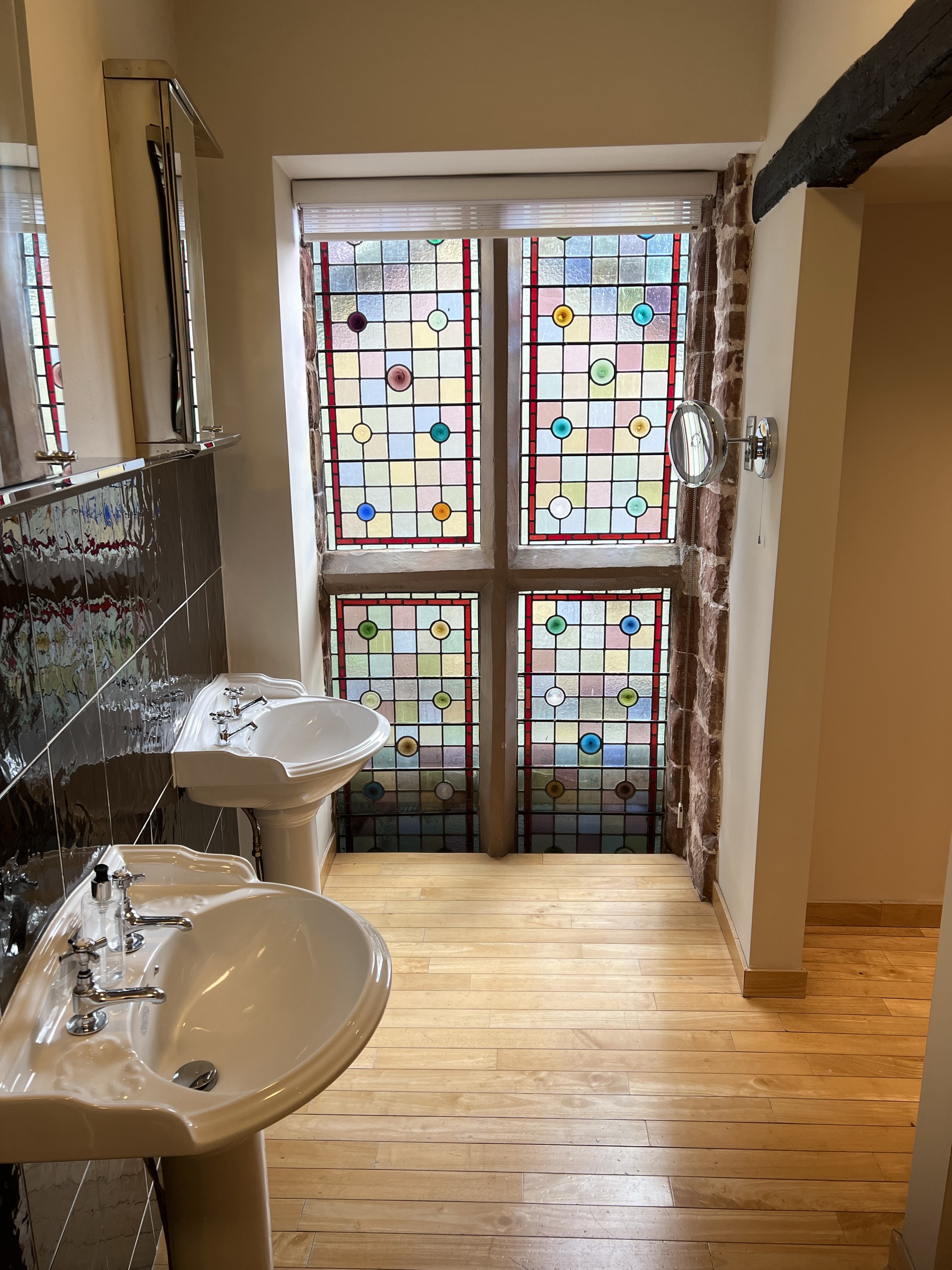 Bathroom with dual pedestal sinks and a striking stained glass window at The Silk House