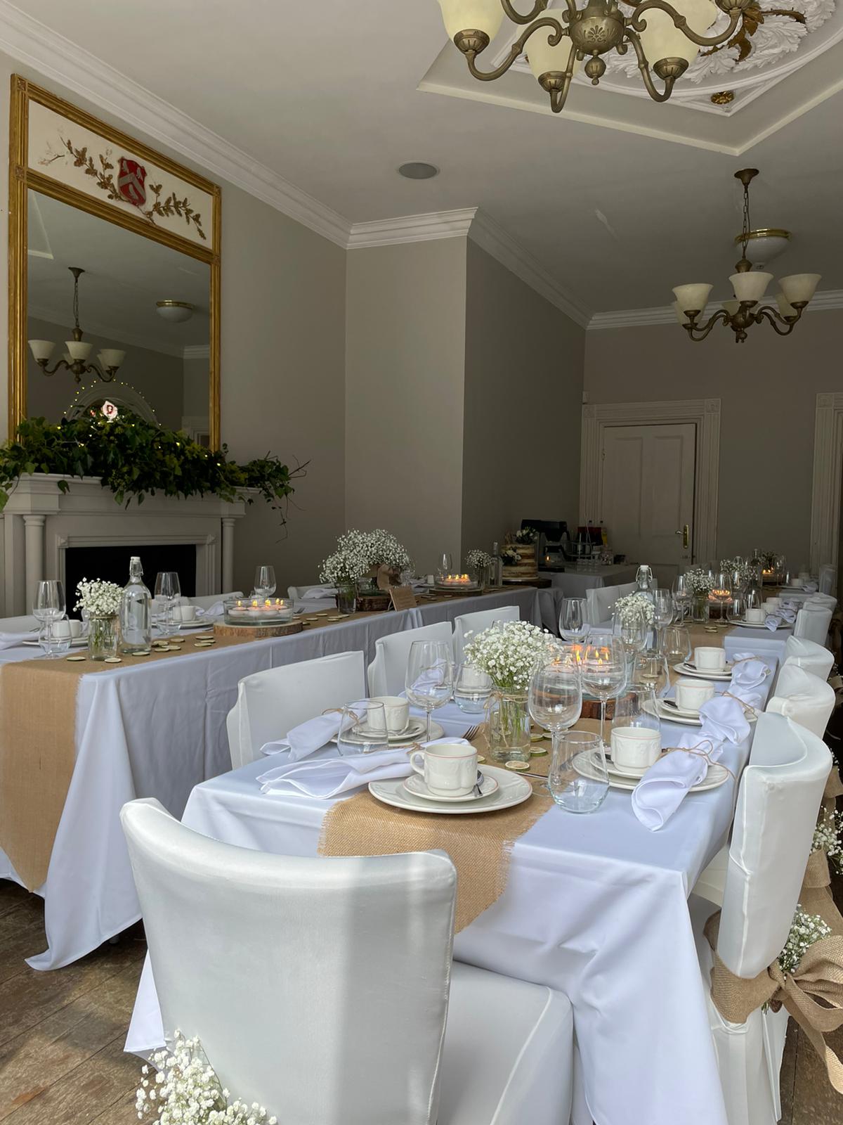 The Silk House function room dressed for a wedding breakfast, with long table, chair sashes and evening lighting